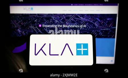 Stoccarda, Germania, 10-23-2022: Persona che detiene il cellulare con il logo della società statunitense di semiconduttori KLA Corporation sullo schermo davanti all'azienda Foto Stock