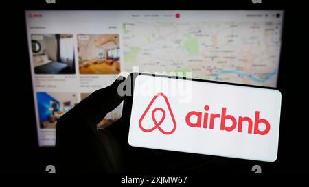 Stoccarda, Germania, 11-30-2022: Persona che tiene il cellulare con il logo della società americana Airbnb Inc. Sul display di fronte Foto Stock