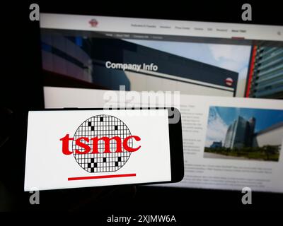 Stoccarda, Germania, 11-30-2022: Persona con smartphone con logo della Taiwan Semiconductor Manufacturing Company (TSMC) sullo schermo di fronte Foto Stock