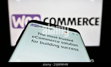Stoccarda, Germania, 12-02-2022: Telefono cellulare con pagina web della soluzione di e-commerce open-source WooCommerce sullo schermo davanti al logo aziendale. Concentrati Foto Stock