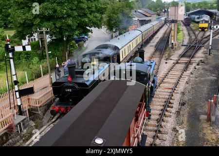 Il carro armato GWR 1366 classe 1369 arriva a Buckfastleigh sulla South Devon Railway. Come il carro armato pannier GWR classe 6400 n. 6412 attende di partire. Foto Stock