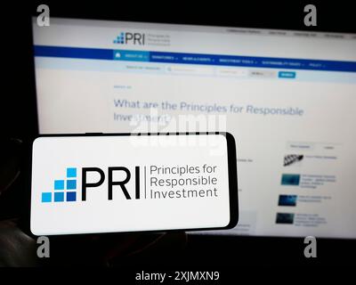 Stoccarda, Germania, 12-19-2022: Persona che possiede uno smartphone con il logo dei principi ONU per gli investimenti responsabili (PRI) sullo schermo davanti al sito web. Foto Stock