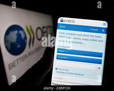 Stoccarda, Germania, 12-23-2022: Persona che detiene un cellulare con pagina web dell'organizzazione intergovernativa OCSE sullo schermo davanti al logo. Concentrati su Foto Stock