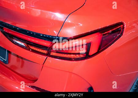 Gruppi di luci posteriori rosse e carrozzeria arancione su un'auto esposta sotto illuminazione interna. Foto Stock