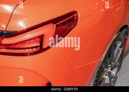Gruppi di luci posteriori rosse e carrozzeria arancione su un'auto esposta sotto illuminazione interna. Foto Stock