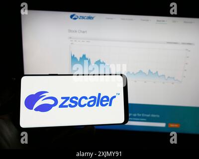 Stoccarda, Germania, 12-30-2022: Persona che detiene un telefono cellulare con il logo della società americana di sicurezza sul cloud Zscaler Inc. Sullo schermo davanti alla pagina web. Foto Stock