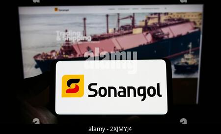 Stoccarda, Germania, 01-06-2023: Persona che tiene il cellulare con il logo della società petrolifera angolana Group Sonangol sullo schermo davanti all'azienda Foto Stock