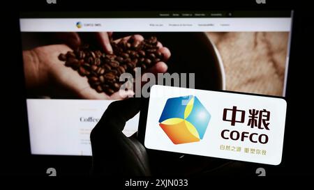 Stoccarda, Germania, 12-25-2022: Persona che tiene il cellulare con il logo della China Oil and Foods Corporation (COFCO) sullo schermo davanti alla pagina web. Foto Stock