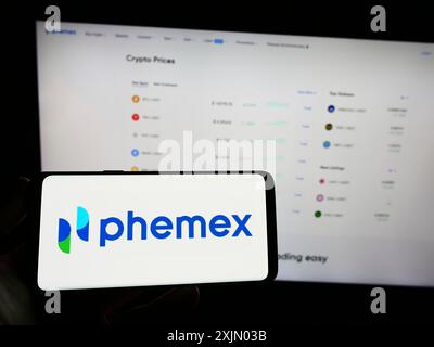 Stoccarda, Germania, 12-31-2022: Persona in possesso di uno smartphone con logo del cambio di criptovaluta Phemex sullo schermo di fronte al sito web. Concentrati sul telefono Foto Stock