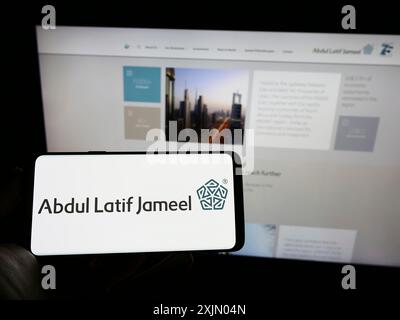 Stoccarda, Germania, 12-25-2022: Persona che detiene il cellulare con il logo della società saudita Abdul Latif Jameel (ALJ) sullo schermo di fronte alla pagina web. Foto Stock