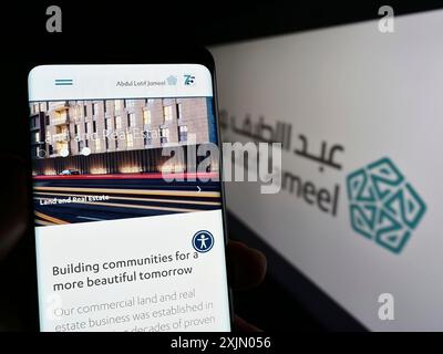 Stoccarda, Germania, 12-25-2022: Persona che detiene il cellulare con pagina web della società saudita Abdul Latif Jameel (ALJ) sullo schermo con logo. Concentrati su Foto Stock