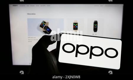 Stoccarda, Germania, 01-15-2023: Persona che detiene un telefono cellulare con il logo della società cinese di elettronica di consumo OPPO sullo schermo di fronte all'azienda Foto Stock