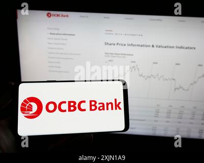 Stoccarda, Germania, 01-12-2023: Persona che possiede un telefono cellulare con il logo della Oversea-Chinese Banking Corporation (OCBC Bank) sullo schermo davanti al web Foto Stock