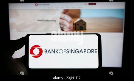 Stoccarda, Germania, 01-12-2023: Persona che detiene un cellulare con il logo della società di servizi finanziari Bank of Singapore sullo schermo davanti all'azienda Foto Stock