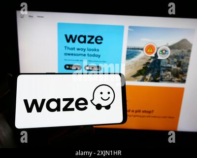Stoccarda, Germania, 01-16-2023: Persona con smartphone con logo della società di navigazione israeliana Waze Mobile Ltd. Sullo schermo davanti al sito web. Foto Stock