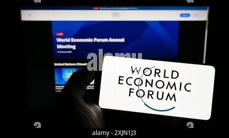 Stoccarda, Germania, 01-21-2023: Persona con smartphone con logo dell'organizzazione World Economic Forum (WEF) sullo schermo davanti al sito web. Concentrati Foto Stock