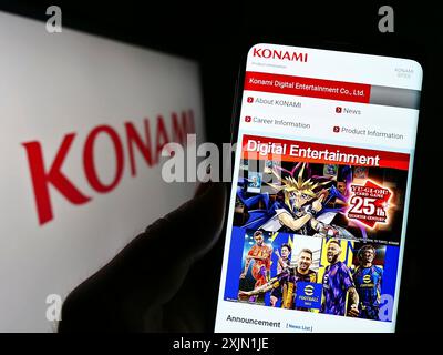 Stoccarda, Germania, 01-21-2023: Persona che detiene il cellulare con pagina web della società giapponese Konami Group Corporation sullo schermo davanti al logo. Concentrati Foto Stock