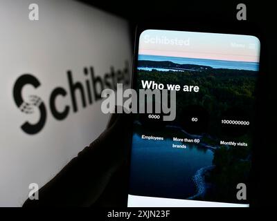 Stoccarda, Germania, 01-28-2023: Persona che detiene il cellulare con il sito web della società norvegese Schibsted Media Group sullo schermo davanti al logo. Concentrati su Foto Stock