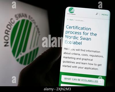 Stoccarda, Germania, 03-11-2023: Persona che detiene un cellulare con pagina web di certificazione ambientale Nordic Ecolabel sullo schermo davanti al logo. Foto Stock