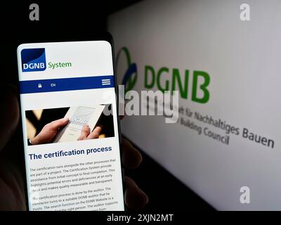 Stoccarda, Germania, 03-11-2023: Persona che detiene un telefono cellulare sullo schermo del sito web della Deutsche Gesellschaft fuer Nachhaltiges Bauen (DGNB). Concentrati su Foto Stock