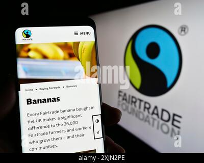 Stoccarda, Germania, 03-11-2023: Persona che possiede uno smartphone con il sito web dell'organizzazione benefica The Fairtrade Foundation sullo schermo con il logo. Concentrati su Foto Stock