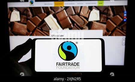 Stoccarda, Germania, 03-11-2023: Persona con smartphone e logo dell'organizzazione benefica The Fairtrade Foundation sullo schermo di fronte al sito web. Foto Stock