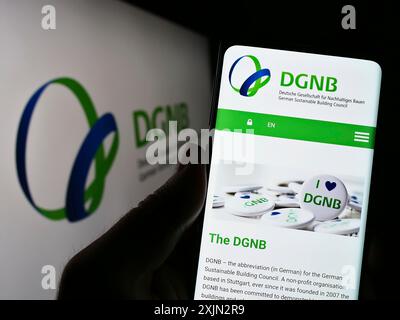 Stoccarda, Germania, 03-11-2023: Persona che tiene il cellulare con pagina web della Deutsche Gesellschaft fuer Nachhaltiges Bauen (DGNB) sullo schermo con il logo. Foto Stock