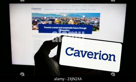 Stoccarda, Germania, 03-10-2023: Persona che detiene un cellulare con il logo della società di tecnologia edile Caverion Oyj sullo schermo davanti all'azienda Foto Stock
