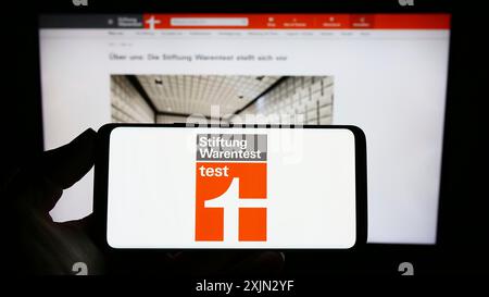 Stoccarda, Germania, 03-10-2023: Persona con smartphone e logo di Stiftung Warentest, sullo schermo di fronte al sito web. Foto Stock