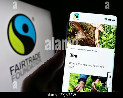 Stoccarda, Germania, 03-11-2023: Persona con smartphone e pagina web dell'organizzazione benefica The Fairtrade Foundation sullo schermo con logo. Concentrati Foto Stock