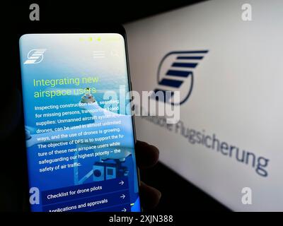 Stoccarda, Germania, 03-18-2023: Persona che possiede uno smartphone con pagina web del controllo del traffico aereo DFS Deutsche Flugsicherung sullo schermo con logo. Concentrati Foto Stock