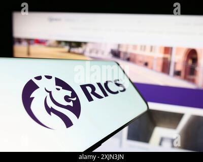 Stoccarda, Germania, 03-18-2023: Smartphone con logo della Royal Institution of Chartered Surveyors (RICS) sullo schermo davanti al sito Web. Concentrati su Foto Stock