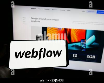 Stoccarda, Germania, 03-31-2023: Persona che tiene il cellulare con il logo della società americana di software di sviluppo web Webflow Inc. Sullo schermo con il sito web. Foto Stock