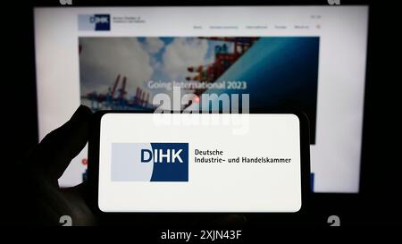 Stoccarda, Germania, 03-24-2023: Persona con smartphone con logo Deutsche industrie- und Handelskammer (DIHK) sullo schermo davanti al sito web. Foto Stock