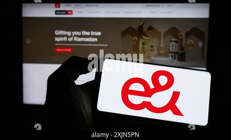 Stoccarda, Germania, 04-23-2023: Persona che detiene un cellulare con il logo di Emirates Telecommunications Group (etisalat) sullo schermo davanti alla pagina web. Foto Stock