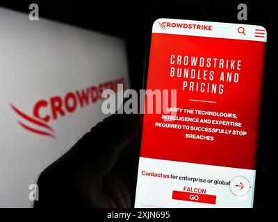Stoccarda, Germania, 03-31-2023: Persona che detiene il cellulare con pagina web della società di sicurezza informatica CrowdStrike Holdings Inc. Su schermo con logo. Concentrati Foto Stock