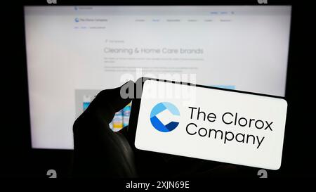 Stoccarda, Germania, 03-31-2023: Persona che tiene il cellulare con il logo del produttore statunitense di prodotti chimici Clorox Company sullo schermo davanti al logo aziendale. Foto Stock