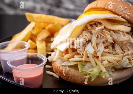 Delizioso sandwich di pollo grattugiato con formaggio, uova e patatine. Maionese Foto Stock
