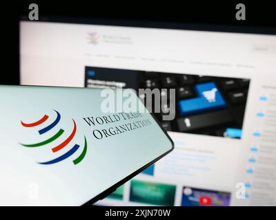 Stoccarda, Germania, 03-25-2023: Telefono cellulare con logo dell'Organizzazione mondiale del commercio (OMC) sullo schermo davanti al sito web. Concentrati al centro a sinistra del telefono Foto Stock