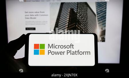 Stoccarda, Germania, 03-19-2023: Persona con smartphone con logo dell'applicazione software Microsoft Power Platform sullo schermo davanti al sito Web. Foto Stock