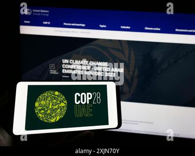 Stoccarda, Germania, 03-25-2023: Persona che tiene un cellulare con il logo della conferenza ONU sui cambiamenti climatici COP28 (Dubai) sullo schermo davanti alla pagina web. Concentrati Foto Stock