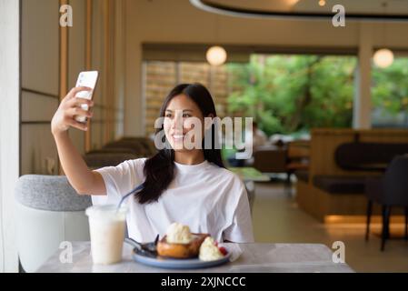 Giovane donna thailandese che gusta il dessert al concetto Coffee Shop Foto Stock