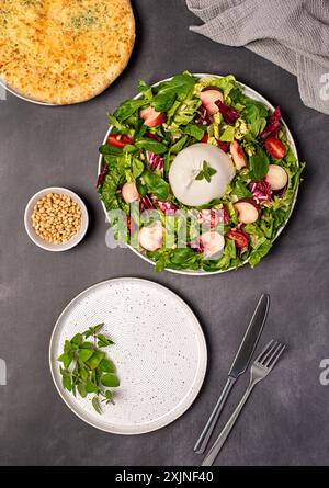 Fotografia gastronomica di insalata con burrata e pesche; mozzarella, formaggio; lattuga, radicchio, foglia, pomodoro; pane tostato; pane all'aglio; origano, pinoli, pep Foto Stock