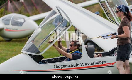 PRODUZIONE - 18 luglio 2024, Assia, Gersfeld (Röhn): Dierk Althoff (l), allievo di volo a vela, chiude il tetto dell'aereo da addestramento. La scuola di volo Wasserkuppe è la più antica scuola di volo in aliante del mondo: Ha 100 anni. Foto: Andreas Arnold/dpa Foto Stock