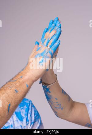 Coppia felice a una festa di rivelazione di genere. La foto mostra la mano di un uomo e di una donna, spalmata di vernice blu. Sto aspettando un bambino Foto Stock