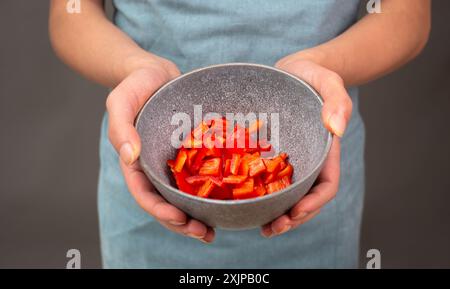 Peperoni rossi a fette in una ciotola, preparare cibo sano con verdure di paprika, tenendo in mano la nutrizione biologica fresca Foto Stock