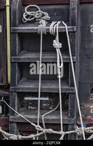 Primo piano di una scala di legno con corde legate intorno ad essa, su una barca. Foto Stock