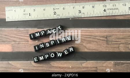 Concetto di Impact Insipire Empower scritto su blocchi di legno. Immagine con elaborazione incrociata su sfondo in legno Foto Stock