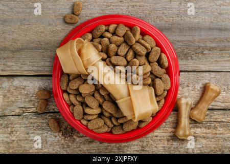 Cibo secco per cani e snack (masticando le ossa) su pavimento di legno, su una superficie piana Foto Stock