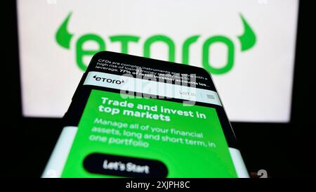 Stoccarda, Germania, 06-17-2023: Telefono cellulare con pagina web della società di social trading israeliana eToro sullo schermo davanti al logo aziendale. Concentrati su Foto Stock